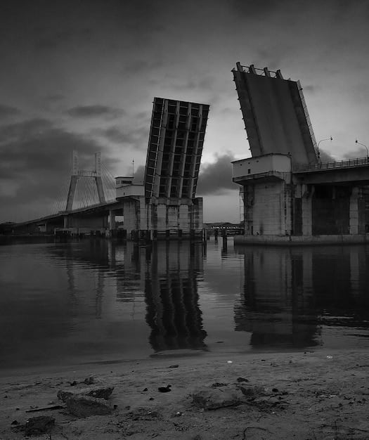 A grayscale photograph showing the ruins of a city after a nuclear explosion. The scene is filled with debris, twisted metal, and crumbling buildings. In the distance, a faint mushroom cloud can be seen. The sky is filled with smoke and ash. The image should convey a sense of utter destruction and desolation.