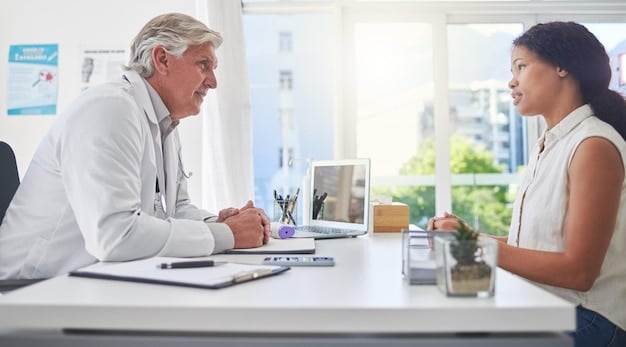 A doctor in a brightly lit office giving a check-up to a patient via a video call on a laptop. The patient is smiling and nodding, indicating a positive experience. The background shows a modern medical office with anatomical models on the shelves.