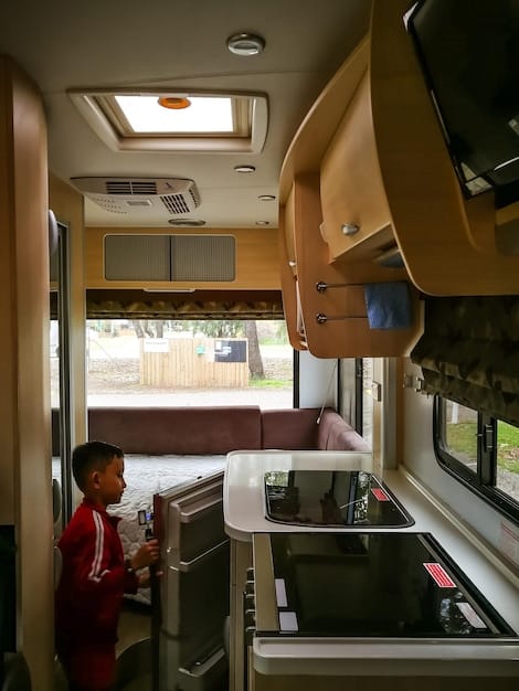 Inside view of a well-equipped Class C RV, showing the kitchen, dining area, and sleeping space.