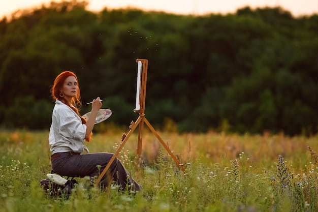 A photographer setting up a tripod in a field of wildflowers with a mountain range in the background. The sun is rising, casting a warm glow over the scene.