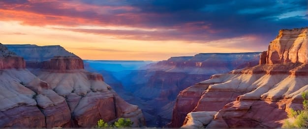 A panoramic view of the Grand Canyon National Park, Arizona, with layers of colorful rock formations stretching to the horizon and a clear blue sky above.