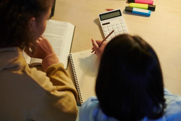 Close-up of a teacher assisting a student with a math problem at their desk. Both are focused and engaged, with the teacher pointing to a specific part of the worksheet. The classroom environment is supportive and encouraging.